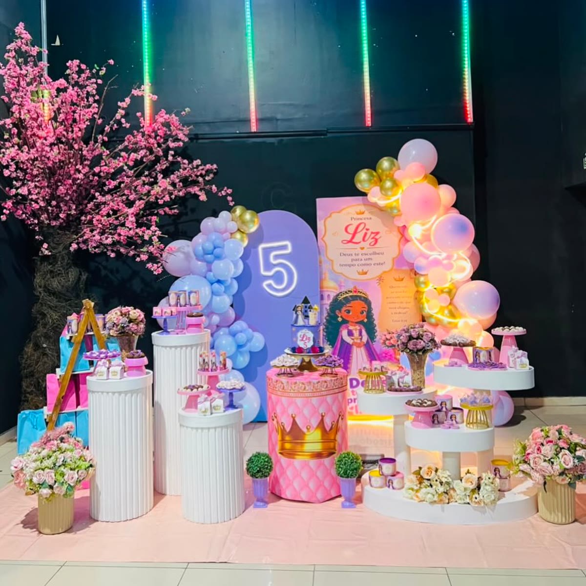 Mesa de aniversário decorada com balões e luzes em um parque Planet Park